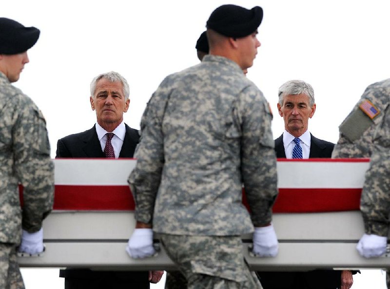Defense Secretary Chuck Hagel (left) and Army Secretary John McHugh pay their respects Wednesday as an Army team transfers the remains of Pfc. Cody Patterson, 24, of Philomath, Ore., and four other servicemen who died in Afghanistan from a transport plane at Dover Air Force Base, Del. 