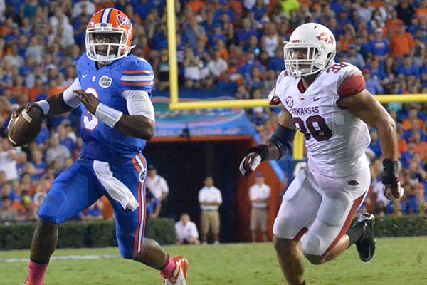 Arkansas defender Jarrett Lake chassis Florida quarterback Tyler Murphy out of the pocket during Saturday night's game at Ben Hill Griffin Stadium in Gainesville, Fla. 