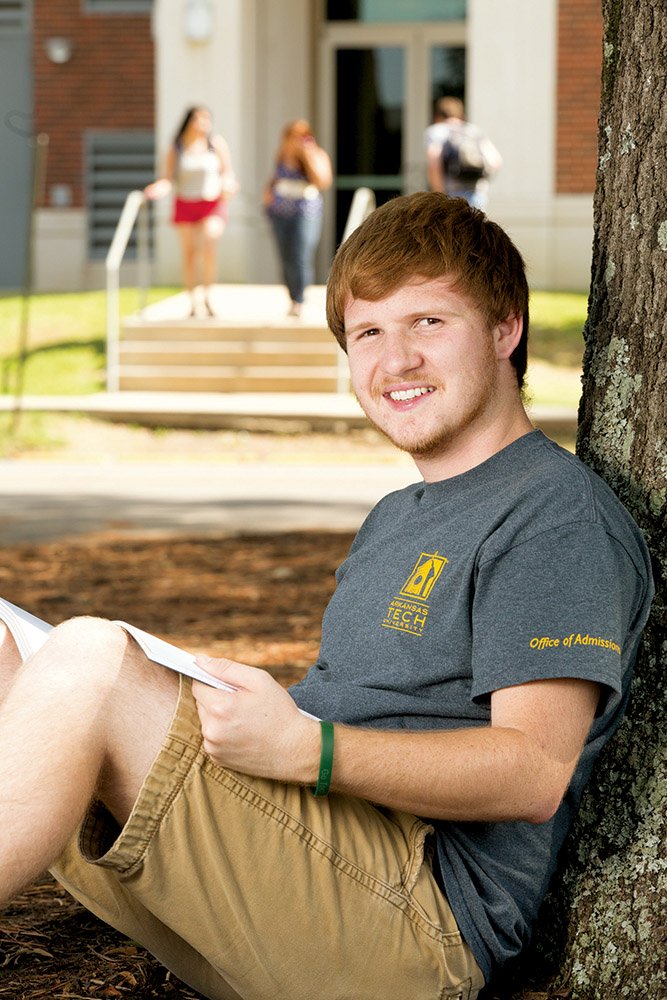 Clay Wyllia of Atkins, a senior at Arkansas Tech University in Russellville, sits under a tree on campus. Wyllia, who works in the Office of Admissions as a tour guide, said he was excited to hear this fall that a record enrollment of 11,000 was reached at the school. Wyllia is Student Government Association president this year.