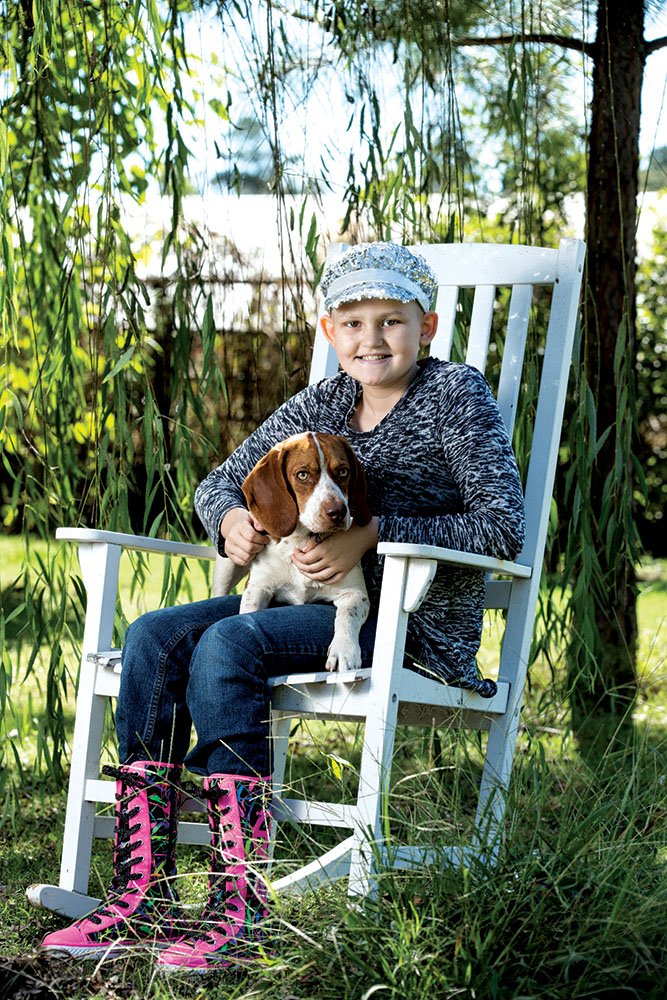 Maddie Windle, 10, holds her dog Hazel in her lap at her home in Aplin near Perryville. Maddie was diagnosed with Wilms’ tumor, a type of kidney cancer, two years ago. Despite the small odds of it reoccurring, her doctor said, she now has cancer for the third time. Maddie enjoys reading and playing cards, and “loves animals,” she said.