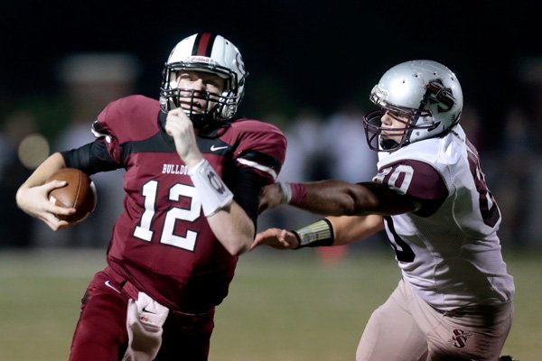 Springdale sophomore quarterback Drake Wymer slips past a tackle attempt from Siloam Springs senior defensive end Ian Austin during the first half on Friday, Oct. 11, 2013, at Bulldog Stadium in Springdale.