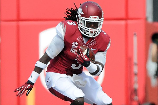 Arkansas' Alex Collins, left, looks to dodge Victor Hampton of South Carolina Saturday, Oct. 12, 2013, during the second quarter of the game against South Carolina at Donald W. Reynolds Razorback Stadium in Fayetteville.