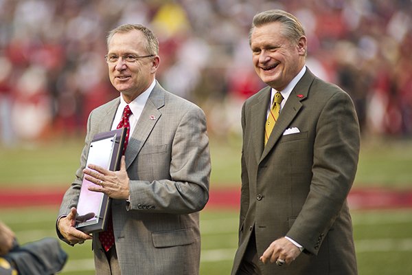 Arkansas Razorback athletic director Jeff Long, left, and chancellor Dave Gearhart walk off the field NCAA college football game against Texas A&M in Fayetteville, Ark., Saturday, Sept. 28, 2013. Long was accepting an award for athletic director of the year. (AP Photo/Beth Hall)