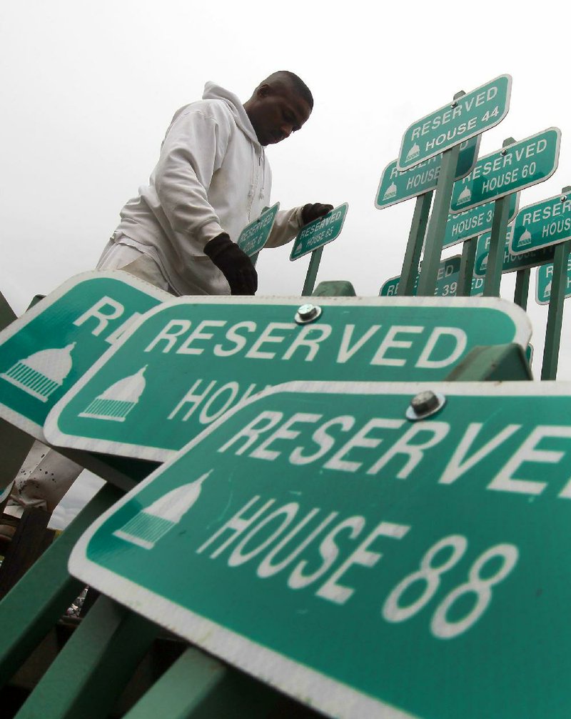 A worker sorts parking signs Wednesday outside the state Capitol in hasty preparation for today’s arrival of legislators for the start of a special legislative session. 