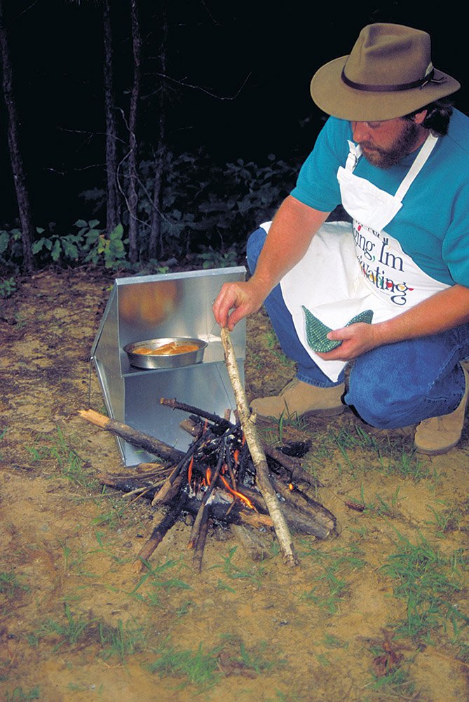 Keith Sutton of Alexander bakes biscuits in a reflector oven beside a campfire. These lightweight, collapsible appliances are great for baking items beside a roaring campfire.
