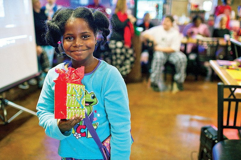 Shiraye Barris, a little sister with Big Brothers Big Sisters of Northeast Arkansas, gets a present at the organization’s annual Christmas party. The Zombie Fun Run 5K race at the beginning of November will provide money for the organization to host more events like this one.