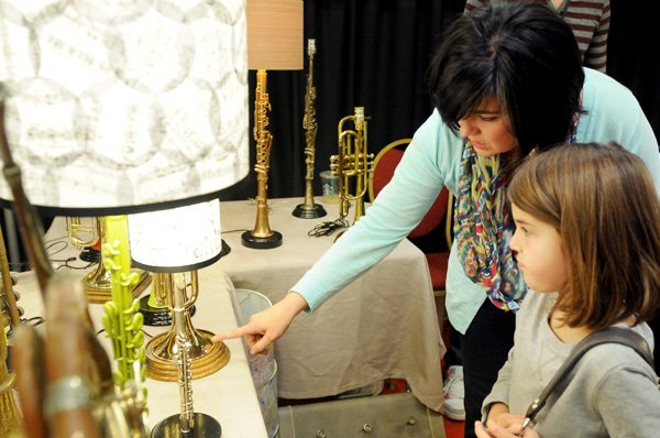 Leslie Lyons and daughter Grace Lyons, 6, look at lamps Saturday made from broken musical instruments by Fayetteville artist Jamie Cornett of Instrumental Lighting at the Ozark Regional Arts & Crafts Festival at the John Q. Hammons Center in Rogers. 