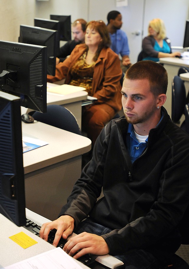 Dustin Breedlove, from Rogers, fills out an application for employment with Serco North America on a computer in the Arkansas Department of Workforce Services Rapid Response unit, an RV equipped with multiple application stations, while it was making a stop at the Center for Nonprofits at St. Mary's in Rogers on Monday.