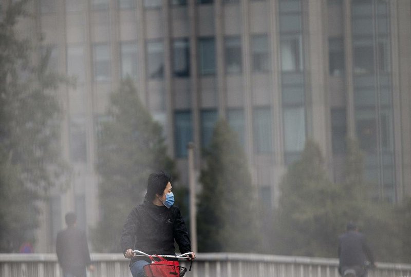 A woman pedals through the haze Tuesday in Beijing. 