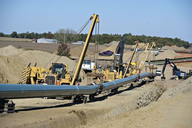 Caterpillar Inc. side booms carry a section of pipe next to a trench during construction of the Flanagan South crude oil pipeline outside of Goodfield, Ill., earlier this month. Caterpillar on Wednesday reported a third-quarter profit of $946 million. 