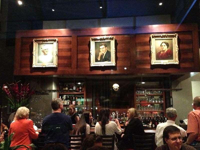 Family portraits, a reminder of the restaurant’s history, hang above the bustling bar at Bruno’s Little Italy’s new downtown location. 
