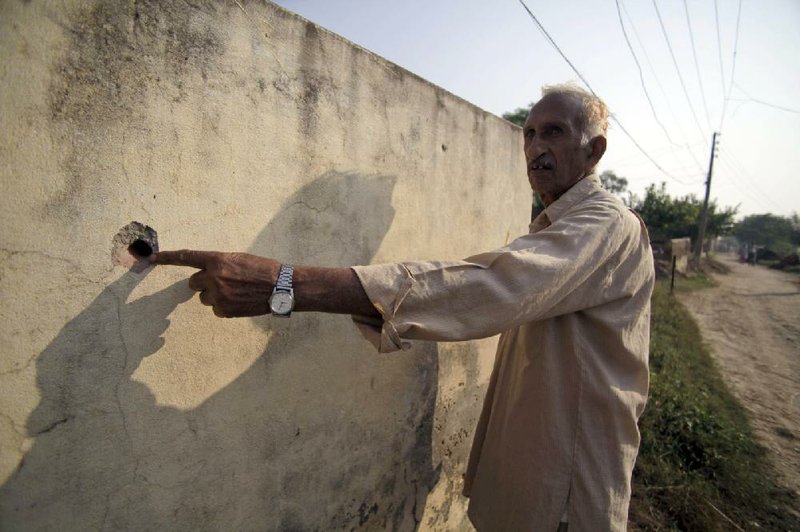 An Indian villager points to the mark of a bullet that he said was fired from the Pakistan side of the border area at Aria. 