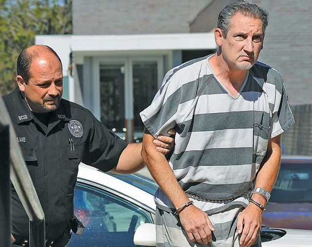 Barry Gebhart, Fayetteville High School athletic director, is escorted into court for his bond hearing Wednesday, Oct. 23, 2013, at the Benton County Courthouse Annex in Bentonville.