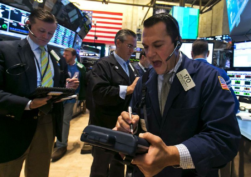 Trader Michael Zicchinolfi (right) works Friday on the floor of the New York Stock Exchange. Positive quarterly earnings reports pushed stock market indexes to record highs. 