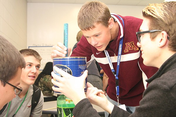 Freshman Ryan Giese, center, measures millimeters of water left in the team's coffee can during a water tower simulation with sophomore classmates, from left, Dexter Decker, Zach Roberts and Spenser Coburn (CQ) in Pre-Advanced Placement Algebra II at New Technology High School on Thursday, Oct. 24, 2013. The team of four gathered experimental data to compare with the theoretical formula used in algebra.