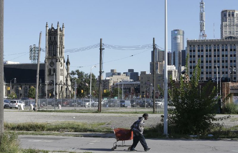 A man walks past an empty lot north of downtown Detroit where a proposed hockey arena and retail development is planned. 