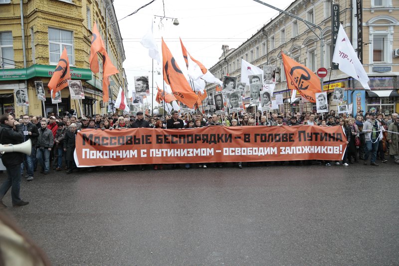 People carry a banner " End Putinism, Free prisoners " during an opposition rally in downtown Moscow, Sunday, Oct. 27, 2013. Several thousand opposition supporters are marching through the Russian capital to demand the release of people they consider political prisoners. (AP Photo/ Ivan Sekretarev )