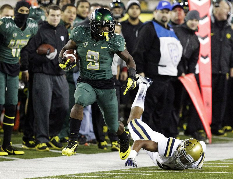 Oregon running back Byron Marshall, left, evades UCLA defender Anthony Jefferson as he heads down the sideline during the second half of an NCAA college football game in Eugene, Ore., Saturday, Oct. 26, 2013. Marshall ran for 133 yards and three touchdowns for a 42-14 victory. (AP Photo/Don Ryan)