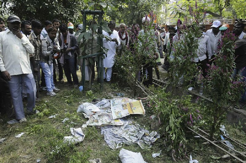 People gather very close to an unexploded  bomb, hidden beneath newspapers before it was defused by officials outside the venue of a political rally in Patna, India, Sunday, Oct. 27, 2013. A series of small bomb blasts killed some people and injured dozens Sunday just hours before a campaign rally by the country’s main opposition prime ministerial candidate Narendra Modi. (AP Photo/Aftab Alam Siddiqui)