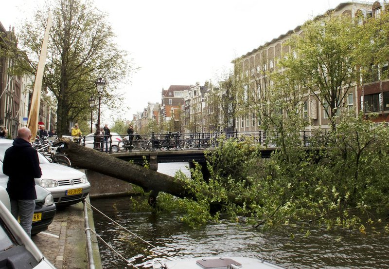 A fallen mature tree blocks the Herengracht canal in Amsterdam, Monday, Oct. 28, 2013. A major storm with hurricane-force gusts lashed southern Britain, the Netherlands and parts of France on Monday, knocking down trees, flooding low areas and causing travel chaos. Amsterdam police said a woman was killed when a tree fell on her in the city and Dutch citizens were warned against riding their bicycles because of the high winds. 
