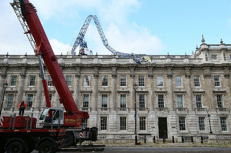 Engineers look at the damage as a crane working on redevelopment at the Cabinet Office in Whitehall, near to Downing Street in London, was brought down by high winds, Monday, Oct. 28, 2013. A major storm with hurricane-force gusts is lashing southern Britain, parts of France and Netherlands,  causing flooding and travel delays with the cancellation of many flights and trains. Weather forecasters say it is one of the worst storms to hit Britain in years.  (AP Photo/Alastair Grant)