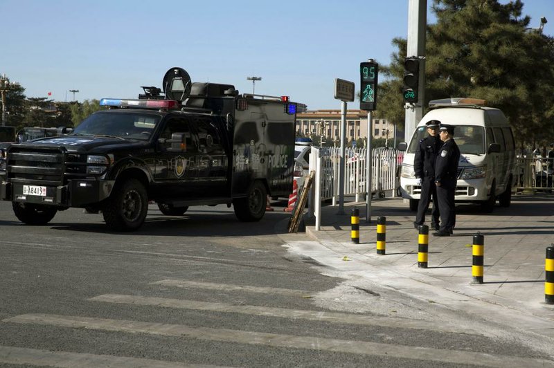 A vehicle of a Chinese police special tactical unit is stationed at the sidewalk Tuesday where it is believed a car drove up before it plowed through a crowd and burned Monday in Beijing. 