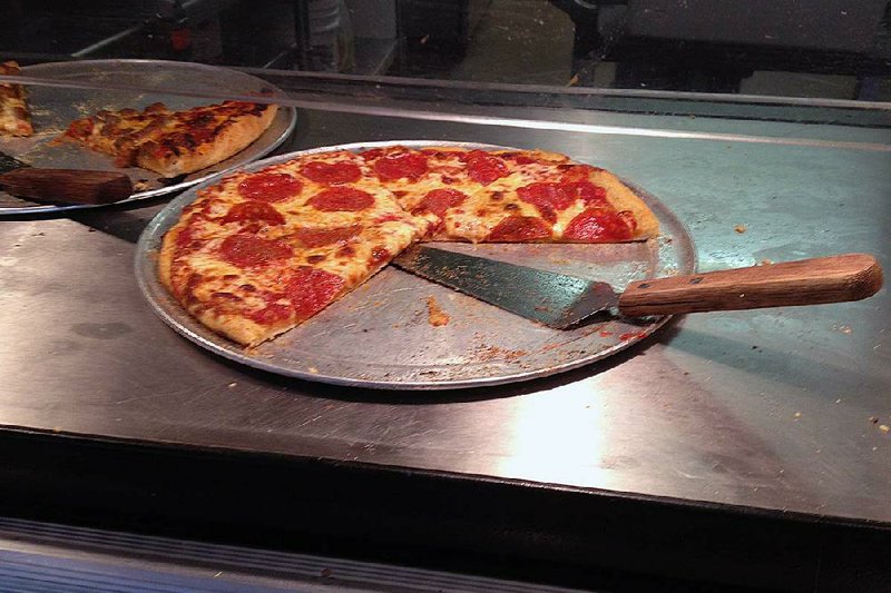A just-baked pepperoni pizza joins pies that had been sitting under the heat lamp for a while on Pizza Hole’s buffet. 