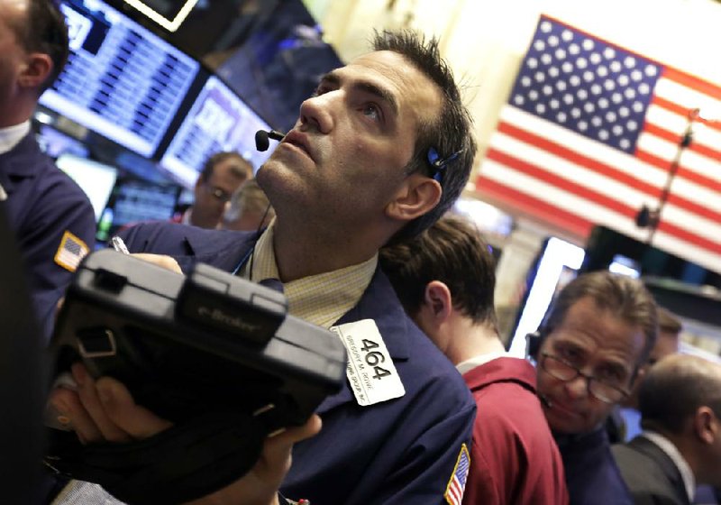Trader Gregory Rowe (left) works Wednesday on the floor of the New York Stock Exchange. The Dow Jones industrial average and Standard & Poor’s 500 indexes fell Wednesday after closing at record highs Tuesday. 