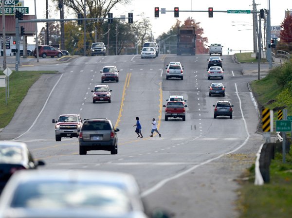 A pair of pedestrians dart across Thompson Street Thursday, Oct. 31, 2013 just north of Backus Avenue in Springdale. Many pedestrians jaywalk across the busy highway to get to and from a shopping center on the west side of the highway.