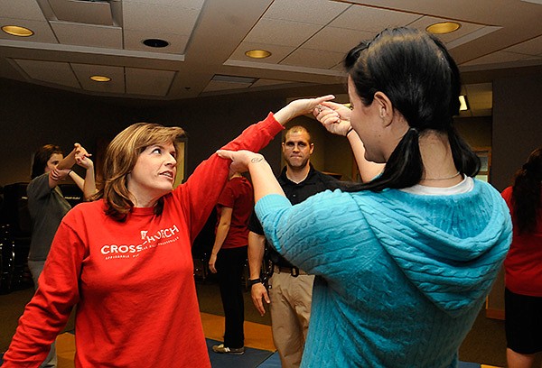 STAFF PHOTO FLIP PUTTHOFF
Donna Culpepper, left foreground, and Beverly Luper, right, practice self-defense techniques on Saturday Nov. 2 2013 that involve bending a foe's fingers. Cpl. Anthony Christiano watches their technique during the self-defense class for women held at the Rogers Police Department.