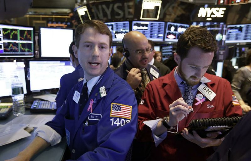 Specialist Peter Elkins (left), works Wednesday with traders Luigi Muccitelli (center) and Timothy Pastina on the floor of the New York Stock Exchange. Stocks rose during the day, sending major indexes to record highs. 