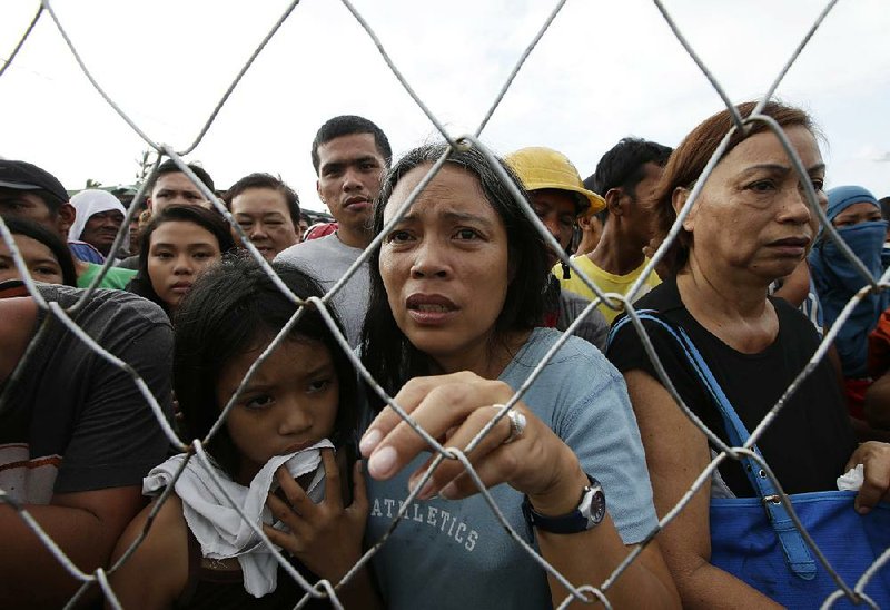 Residents line up Monday to receive treatment and relief supplies at Tacloban airport after Friday’s Typhoon Haiyan lashed the city and several provinces in central Philippines. The islands faced a huge recovery effort as bloated bodies lay uncollected and uncounted in the streets. 