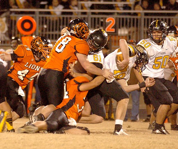 Photo by Randy Moll 
Gravette’s Tyler Kerley (#34) and Jacob Taylor (#78) take down Prairie Grove’s quarterback, Jacob Storlie, as he crosses the line of scrimmage, while Prairie Grove’s Jackson Diebold (#61) blocks and Connor West (#50) looks on during play in Lion Stadium on Friday night. Gravette’s Cody Robinson (#44) is at the left.
