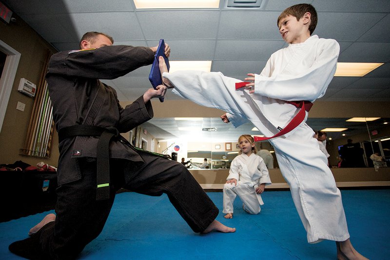 Harrison, 9, practices kicking a board with instructor Scott Yancey during the Bully Busters program at Premier Martial Arts in Cabot. As part of their work through the Stranger Danger initiative, instructors teach children not to give their last names, hoping it will help the youngsters learn how to react to a potential kidnapper.