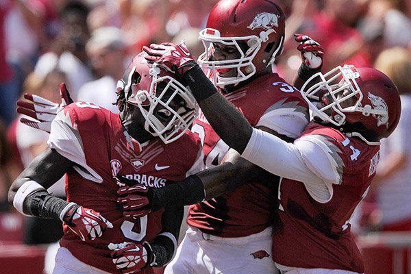 Arkansas defenders Eric Bennett, from right, and Braylon Mitchell celebrate with cornerback Will Hines intercepted a Southern Miss pass in the second quarter of the game in Razorbacks Stadium in Fayetteville on Saturday Sept. 14, 2013.