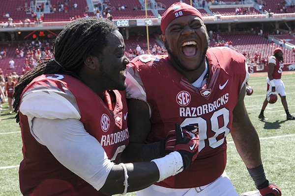 Arkansas running back Alex Collins, left, and defensive tackle Robert Thomas celebrate Saturday, Sept. 14, 2013, after the Hogs' win at Razorback Stadium in Fayetteville.