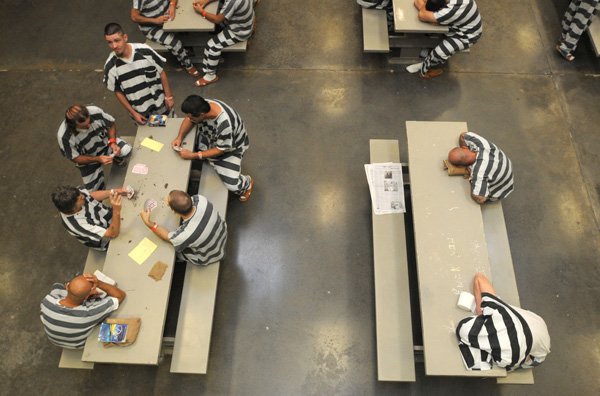 Inmates play cards and sit in a room Wednesday, Sept. 22, 2010, at the Benton County Jail in Bentonville. Some jail inmates are awaiting deportation as part of the federal ICE program, 287(g), that identifies illegal immigrants who are wanted on other criminal charges.