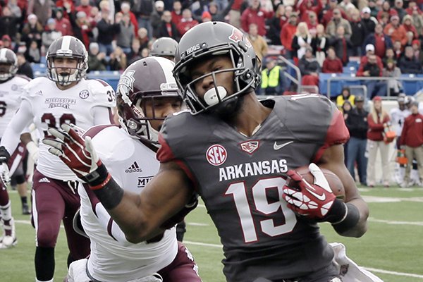 Arkansas wide receiver Javontee Herndon (19) carries to the end zone ahead of Mississippi State defensive back Justin Cox in the first quarter of an NCAA college football game in Little Rock, Ark., Saturday, Nov. 23, 2013. (AP Photo/Danny Johnston)