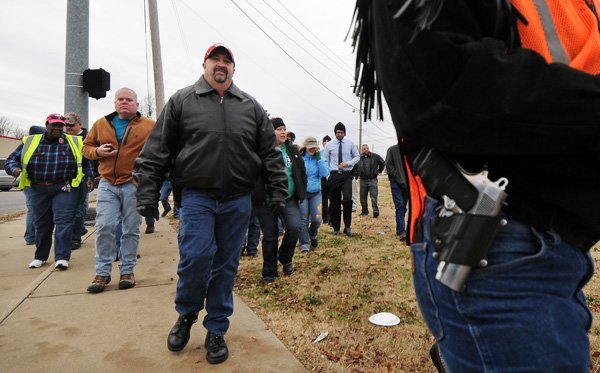 Marty Nelson, from Greenwood, left, follows behind Tony Asher, from Lincoln, who wears a Colt .45 cal pistol on his hip, while participating in a walk along North Thompson Street in Springdale celebrating a new state law, passed on August 16, legalizing open carry of firearms in Arkansas, on Saturday November 23, 2013. Several dozen gun rights supporters joined Northwest Carry, a group associated with Arkansas Carry, in walking a few blocks while openly wearing handguns.