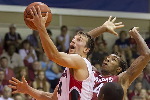 Gonzaga guard Kevin Pangos (4) slips between Arkansas guard Michael Qualls, top right, and guard Fred Gulley III (12) to shoot a layup in the first half of an NCAA college basketball game at the Maui Invitational on Wednesday, Nov. 27, 2013, in Lahaina, Hawaii. (AP Photo/Eugene Tanner)