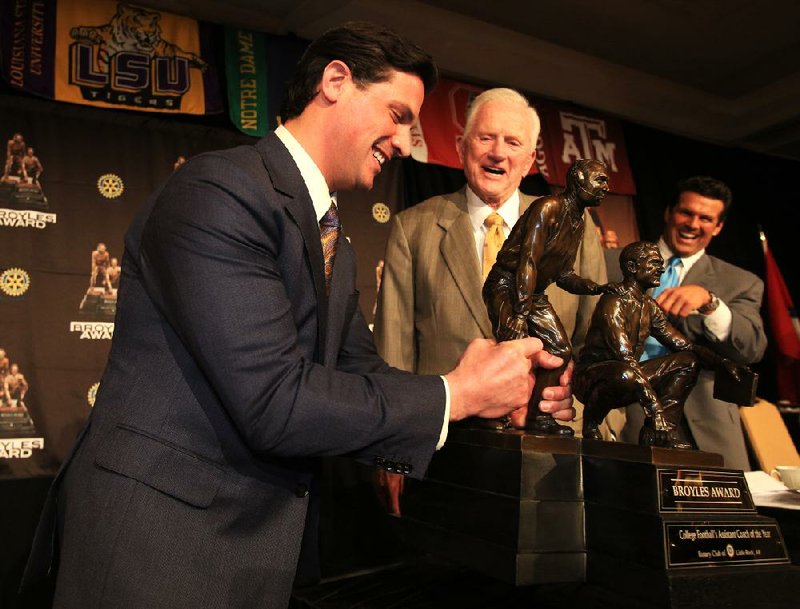 FILE - Notre Dame defensive coordinator Bob Diaco (left) tries to lift the Broyles Award trophy he won Dec. 4, 2012, in Little Rock while Frank Broyles, Arkansas’ former coach and athletic director, and Broyles Award executive director David Bazzel look on.