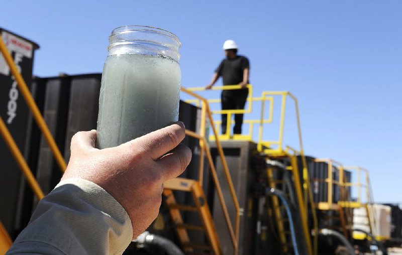 A jar holding waste water from hydraulic fracturing is held up to the light at a recycling site in Midland, Texas, Sept. 24, 2013. The drilling method known as fracking uses huge amounts of high-pressure, chemical-laced water to free oil and natural gas trapped deep in underground rocks. With fresh water not as plentiful companies have been looking for ways to recycle their waste. (AP Photo/Pat Sullivan)