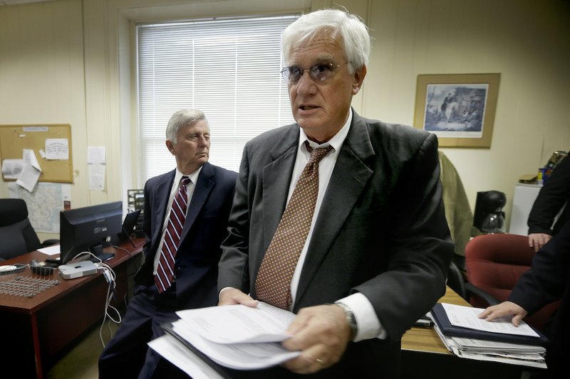 Arkansas Gov. Mike Beebe, left, watches as Arkansas Department of Finance and Administration Director Richard Weiss hands out copies of updated revenue forecasts in the press room at the Arkansas state Capitol in Little Rock, Ark., Monday, Dec. 2, 2013.