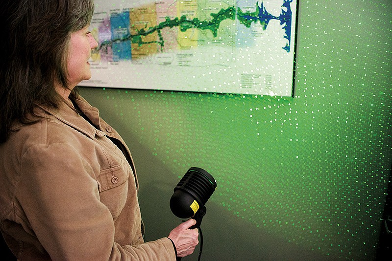 Hot Springs Parks and Recreation Director Jean Wallace demonstrates laser-light projectors used in the Christmas decorations in Hill Wheatley Park. The laser illuminates undecorated trees at night, giving them the look of being ornamented with thousands of lights. Wallace said the project uses just one of the new items purchased at an international trade show in Dallas earlier this year for use in decorating Hot Springs.