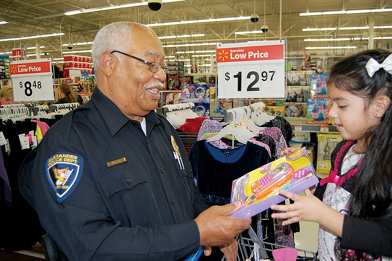 Former Chief Horace Walters of the Alexander Police Department looks over one of the Christmas gifts selected by Anyi Flores during last year’s Shop With Our Cops night in Benton. Bryant police are planning their own Santa With a Badge night, scheduled for Dec. 19.