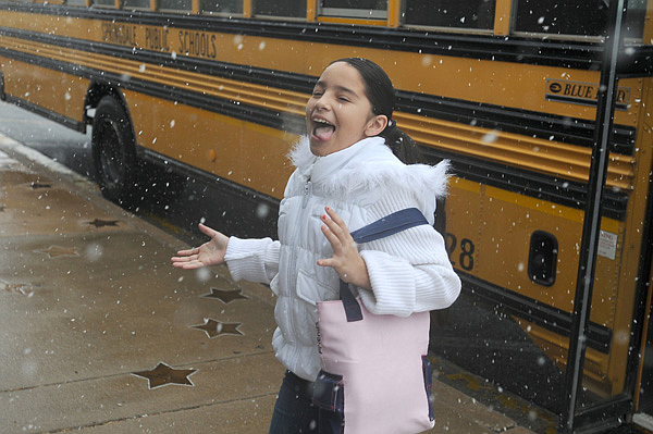 Ashley Munoz, 10, catches snowflakes on her tongue Feb. 20 as she walks from a school bus to the Arts Center of the Ozarks in Springdale earlier this year. Several schools throughout the state have canceled classes Thursday and Friday because of inclement weather.