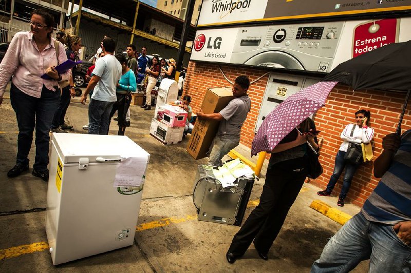 Venezuelans carry discounted electronics and appliances from a store in Caracas last month after the government took over a chain of electronics stores to enforce price controls. It also has blocked websites that publish the black market exchange rate for the Venezuelan bolivar. 