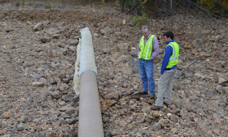 U.S. Rep. Tim Griffin (left) and Central Arkansas Water watershed protection manager John Tynan examine a section of exposed Pegasus pipeline in November in the Lake Maumelle watershed that has been partially covered with a rock protectant held on with duct tape. 