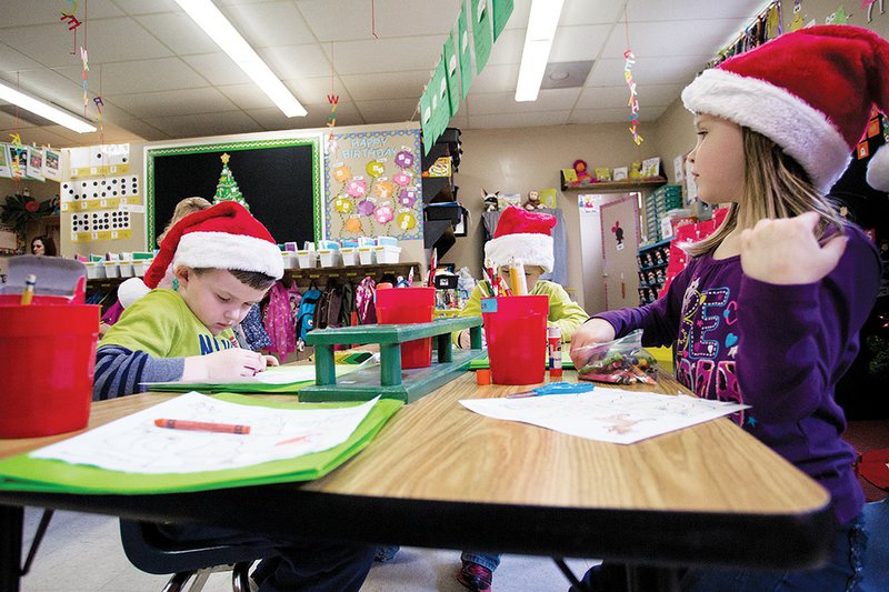 Mason Simmons, left, and Allyson Crockett, right, color their assignments in a kindergarten class at Cave City Elementary School.