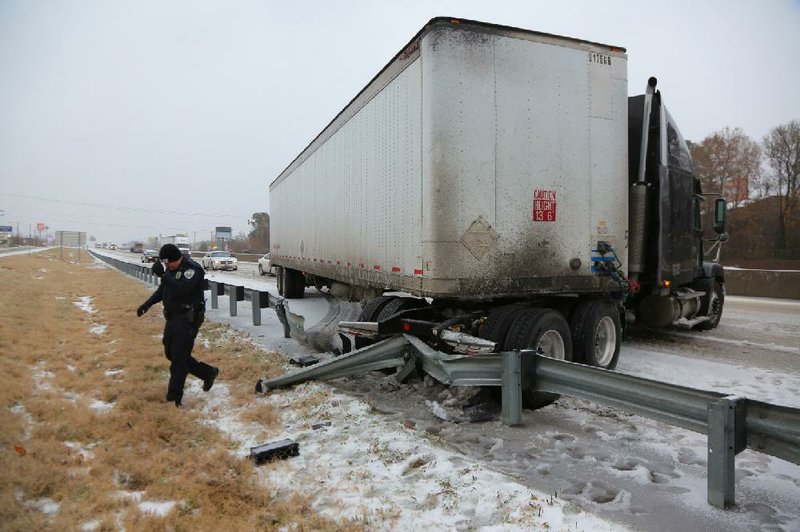 Benton police officer Drew Brown walks away from a big rig that jackknifed Friday morning on an icy stretch of Interstate 30 westbound at Exit 117 in Benton. No one was hurt. 